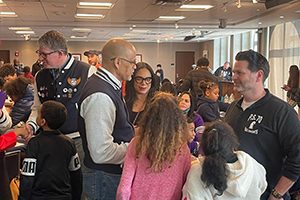 Staff in District 9 varsity jackets greet students and families at PS 11.