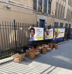 Signs and donation boxes set up along a school fence