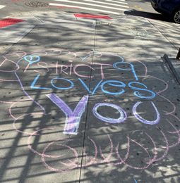 A sidewalk chalk message reading District 9 Loves You