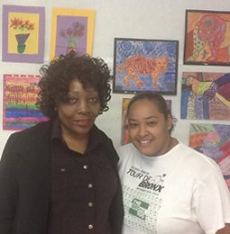 Two educators in front of student artwork